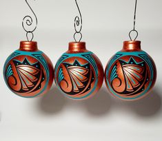 three ornaments hanging from strings with designs on them in the shape of an ornament