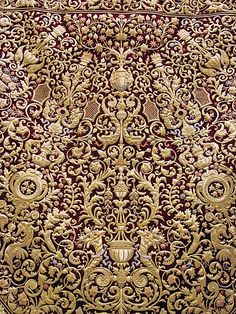 an ornate red and gold wallpaper with intricate designs on it's sides,