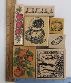 four wooden stamps with pictures of fruits and vegetables on them are shown next to a ruler