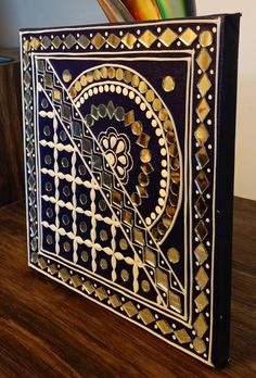 a black and gold book sitting on top of a wooden table next to pencils