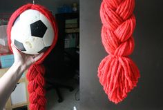 a person holding a soccer ball in their hand next to a red rope hanging from the ceiling