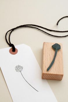 a rubber stamp with a flower on it next to a piece of paper that is attached to a string