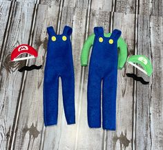 two blue and green onesuits with hats on top of wooden planked floor