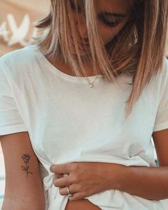 a woman with a flower tattoo on her left arm and right arm behind her back