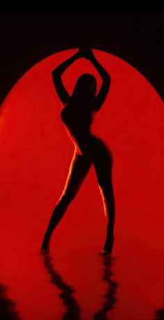 the silhouette of a woman dancing in front of a red circle