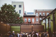 a group of people standing around in an outdoor area with lights strung from the ceiling