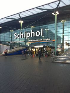 the entrance to an airport terminal with people walking around and stairs leading up to it