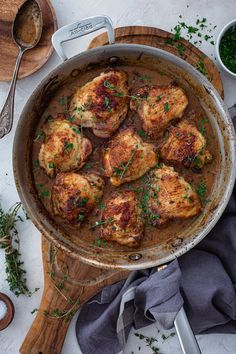 a pan filled with meat and sauce on top of a wooden cutting board