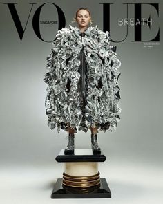 a magazine cover with a woman in a dress made out of silver foil on top of a pedestal