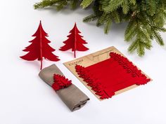 two red christmas trees are next to a piece of paper and a napkin on a white surface