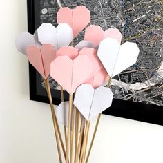 pink and white paper hearts placed on sticks in front of a black framed map,