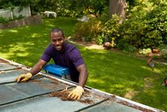 a man laying on top of a roof with his hands in the air and smiling