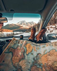 a person sitting in the back seat of a car looking at a map and mountains