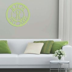 a living room with a white couch, green pillows and a monogrammed wall