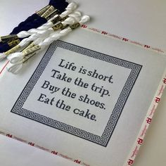 a cross - stitch book with some tassels on it and the words life is short take the trip buy the shoes eat the cake