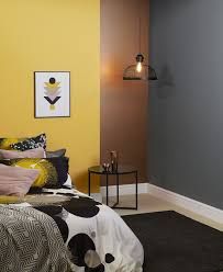 a bedroom with yellow walls, black and white bedding and art on the wall