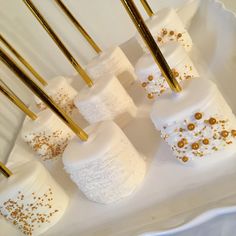 white and gold decorated marshmallows are arranged on a platter with gold sprinkles