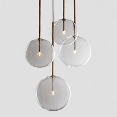 three clear glass globes hanging from brass rods