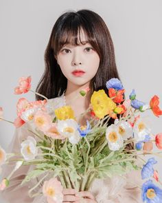 a woman holding a bouquet of flowers in front of her face and looking at the camera