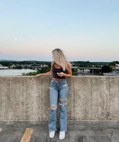 a woman standing on top of a cement wall