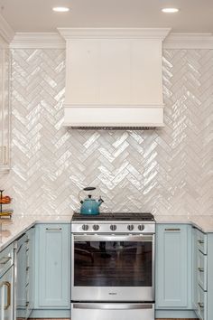 a stove top oven sitting inside of a kitchen next to blue cabinets and counter tops