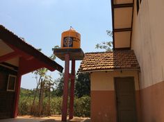 a yellow and blue birdhouse sitting on top of a pole next to a building