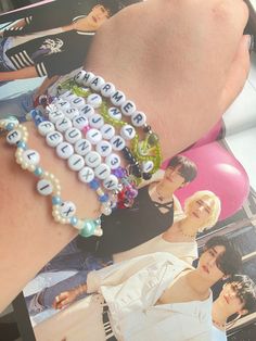 a woman's arm with several bracelets on top of it and pictures behind her