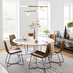 a white table with brown chairs in a living room