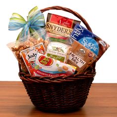 a basket filled with snacks sitting on top of a wooden table next to a blue bow