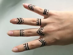 a woman's hand with three different tattoos on her fingers and one has an arrow