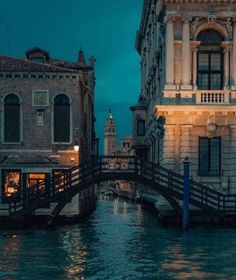 a bridge that is over some water in front of buildings and people walking on it