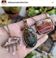 a person is holding three pendants in their hand, one with a cactus on it