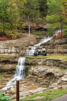 two people riding in an open vehicle near a waterfall