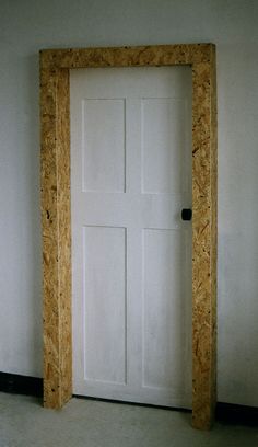 an empty room with a white door and wooden frame on the wall next to it