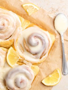 lemon rolls with icing on top next to sliced lemons and a spoon