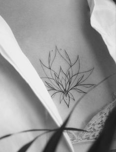 a black and white photo of a woman's stomach with a flower tattoo on it