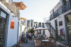 people are sitting at tables under umbrellas on the side walk in an urban setting