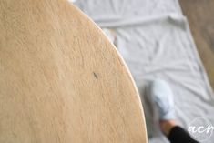 a person standing next to a wooden table on top of a white sheet covered floor