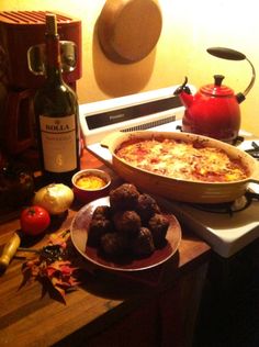 a pizza and other food items on a counter with a bottle of wine in the background