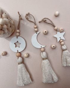 three tasseled ornaments are arranged next to a jar of beads and cotton balls