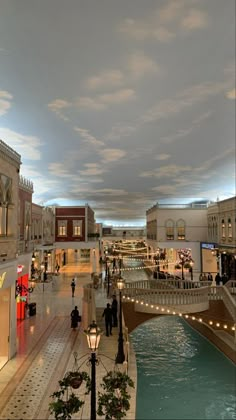 the interior of a shopping mall with people walking around and shops on either side of the walkway