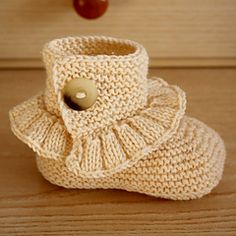 there is a knitted boot with a button on the side and an apple in the background