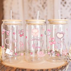 three clear jars with pink bows and hearts on them sitting on a wooden table next to other items