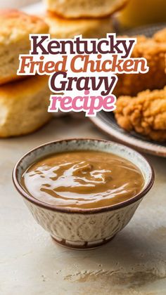 a bowl filled with gravy next to some fried chicken