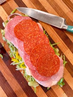 sliced salami on top of lettuce with a knife next to it