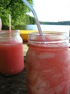 two mason jars filled with pink drink sitting next to each other on top of a wooden table