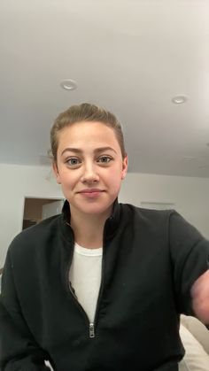 a woman is taking a selfie in the mirror with her cell phone while wearing a black jacket