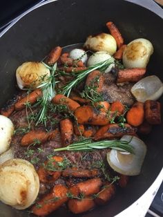 a pot filled with meat, potatoes and carrots on top of a stovetop