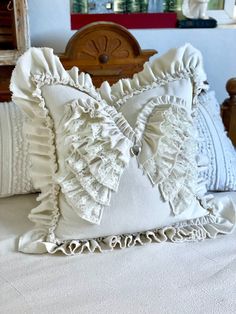 a close up of a pillow on a bed with white linens and ruffled edges