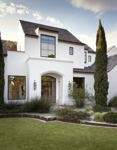 a large white house with lots of trees and bushes in front of the house,